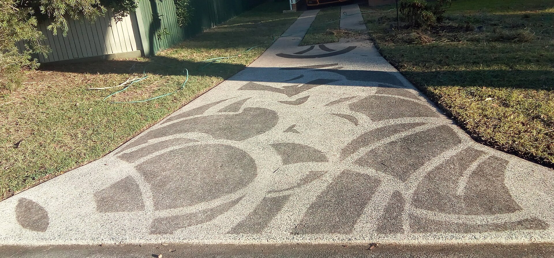 Driveway mid-pressure-wash: dirty surface on one side, freshly cleaned on the other